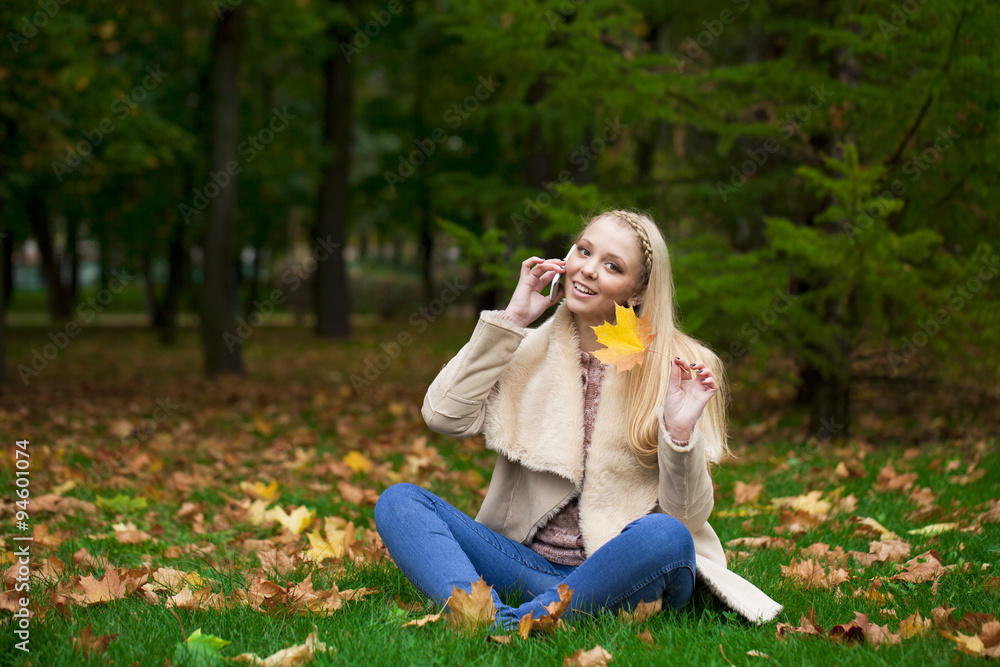 Young happy blonde woman calling by phone in autumn park Young happy blonde woman calling by phone in autumn park