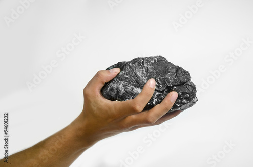 Male hand holding a lump of charcoal over white background