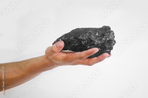 Male hand holding a lump of charcoal over white background