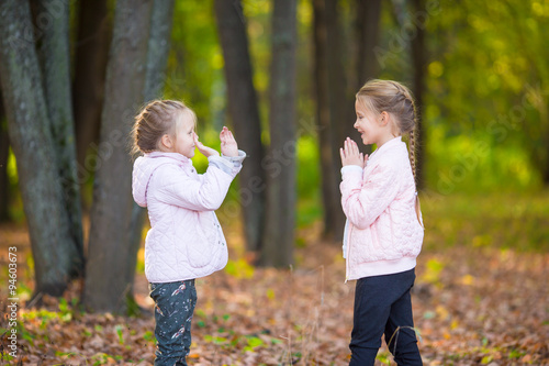 Little adorable girls playing in beautiful autumn park outdoor © travnikovstudio