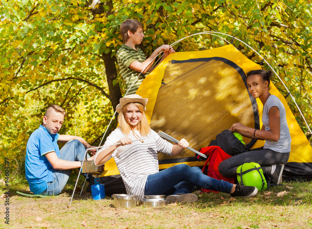 Teenagers build yellow tent during autumn day Teenagers build yellow tent during autumn day