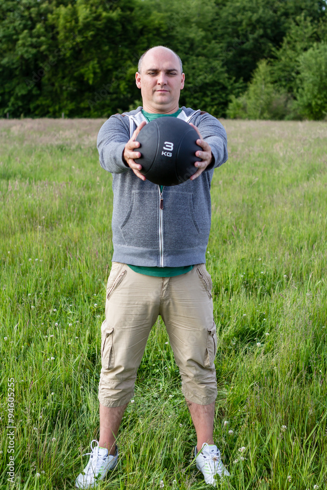 Fototapeta premium Mann trainiert mit 3 Kilo Medizinball im Freien