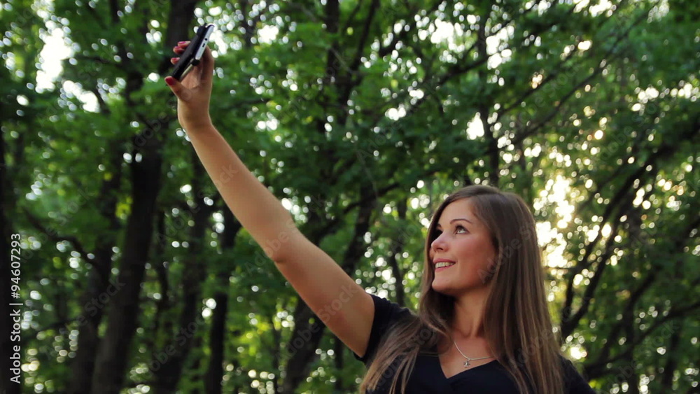 Beautiful girl doing a self-portrait in a park in the sun Beautiful girl doing a self-portrait in a park in the sun
