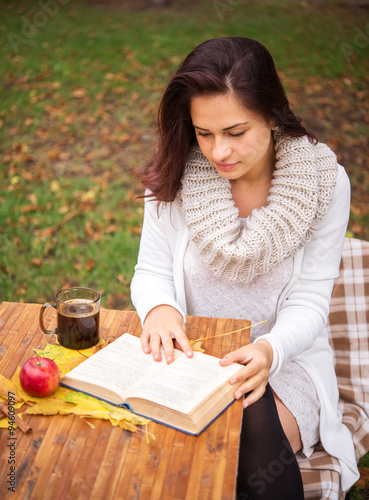 girl reading a book outside in autumn