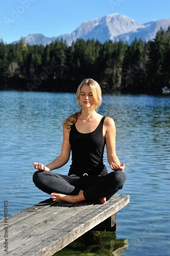 Junge Frau macht Yoga an einem See