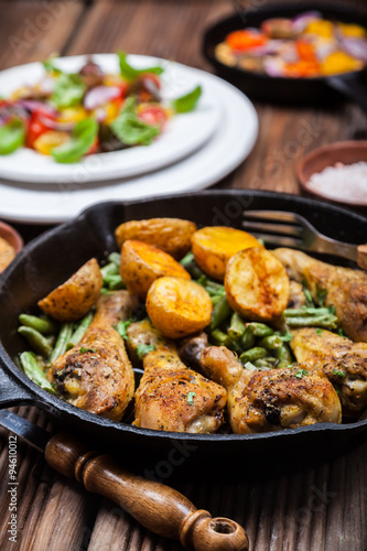 Chicken legs in pan with potatoes and salad