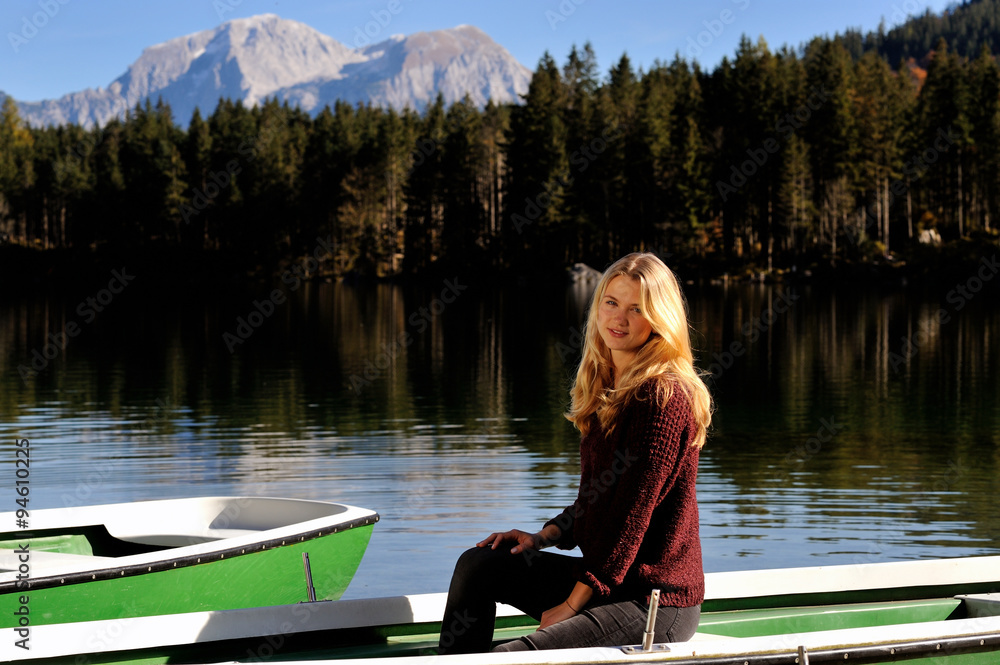 Junge Frau sitzt an einem Bergsee in einem Boot Junge Frau sitzt an einem Bergsee in einem Boot