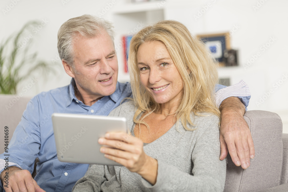 Mature couple sitting in sofa and using tablet pc