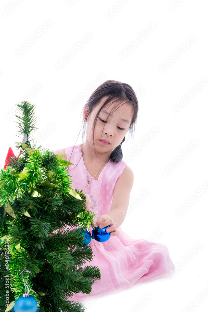 Asian girl helping decorating the Christmas tree, holding some C Asian girl helping decorating the Christmas tree, holding some C