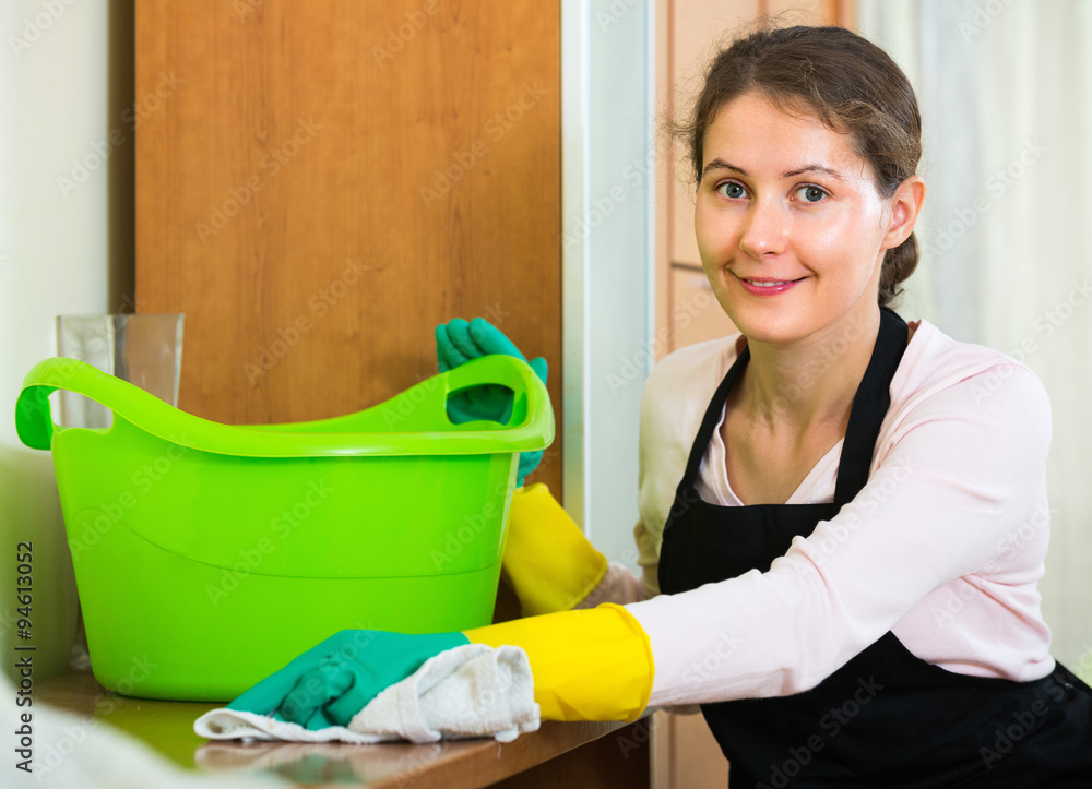 Woman in apron cleaning at home. StockFoto Adobe Stock