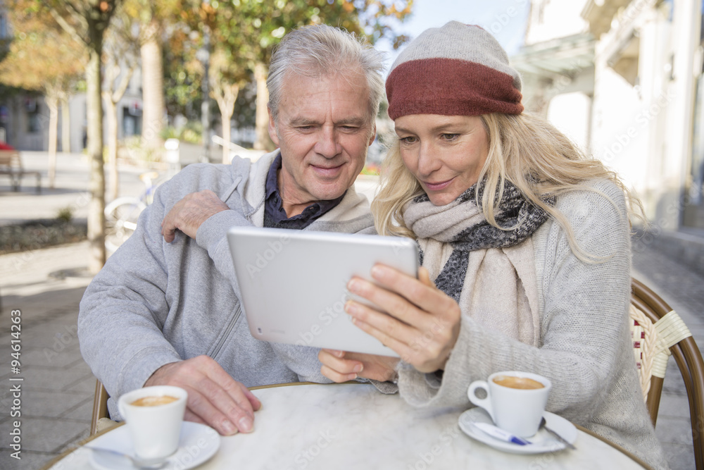 mature couple using a digital tablet at a bar terrace mature couple using a digital tablet at a bar terrace