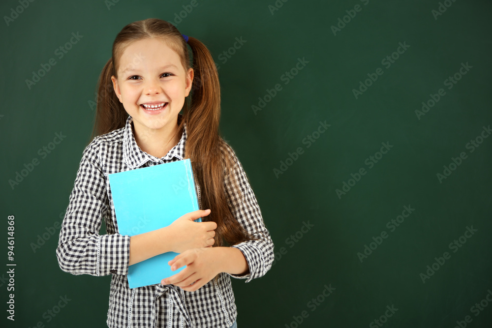 Beautiful little girl with book, on blackboard background Beautiful little girl with book, on blackboard background