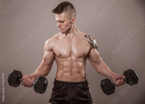 Muscular man exercise with dumbbells.
