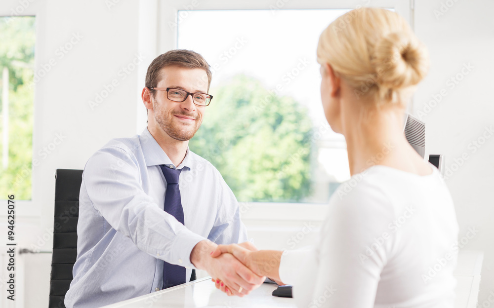 Fototapeta premium Two businesspeople in office with a handshake.