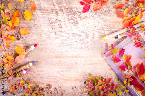Autumn leaves, notebook, diary, pencils lying over wooden background with copy space. Fall and thanksgiving setting. Autumn composition.