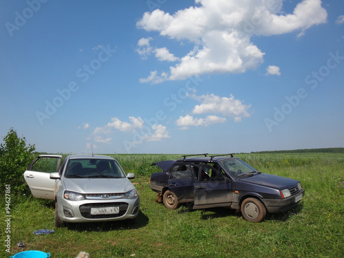 Автомобили на пикнике в поле в летний солнечный день