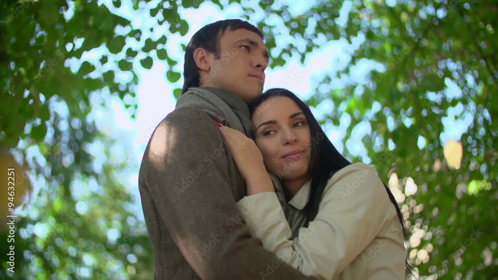 Slow motion shot of serene couple embracing in nature under falling leaves Slow motion shot of serene couple embracing in nature under falling leaves
