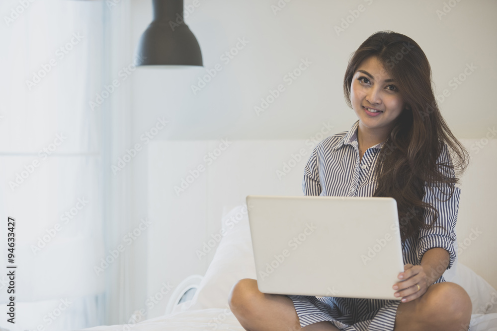 Woman using a laptop computer while lying on her bed, Noise and film grain toned image. Woman using a laptop computer while lying on her bed, Noise and film grain toned image.
