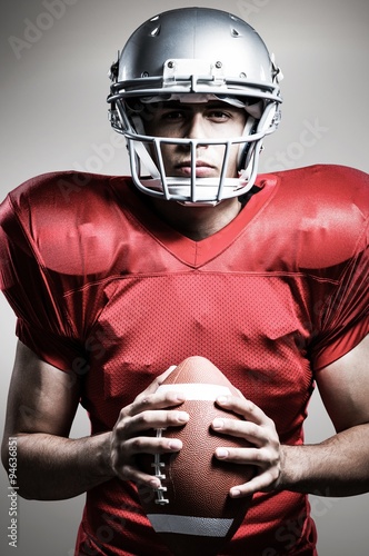 Composite image of american football player holding ball