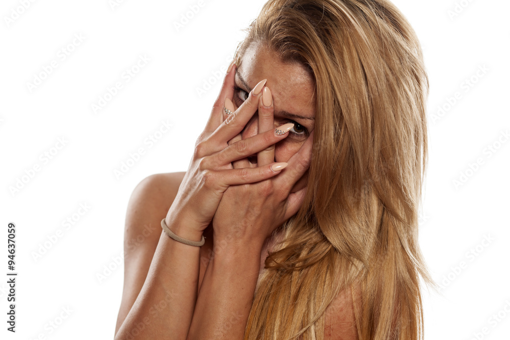 Ashamed smiling young woman looking through her fingers Ashamed smiling young woman looking through her fingers