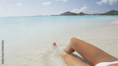 Beach christmas vacation holidays travel conceptWoman wearing santa hat and bikini on holidays travel vacation getaway travel relaxing on tropical beach lying in sand. Beautiful young female model. photo