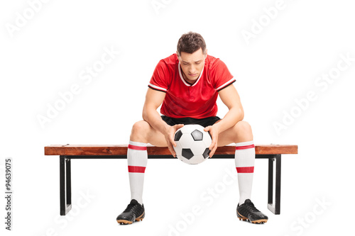 Sad young football player sitting on a bench