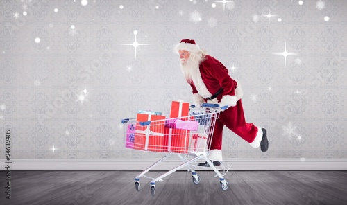 Composite image of santa pushing a shopping cart photo