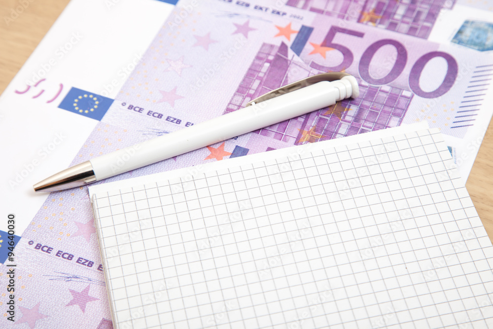 Notepad next to various euro notes Notepad next to various euro notes