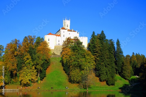 Castle on hill with trees and relaxing people, in autumn 