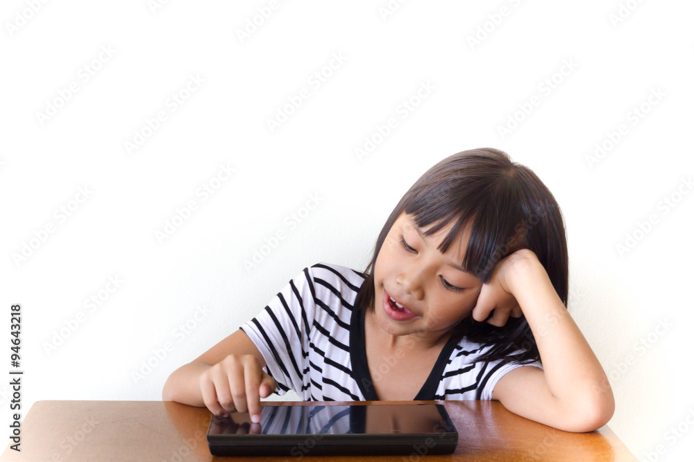 Little girl with joyful tablet pc sitting on the wooden table - Technology and children concept Little girl with joyful tablet pc sitting on the wooden table - Technology and children concept