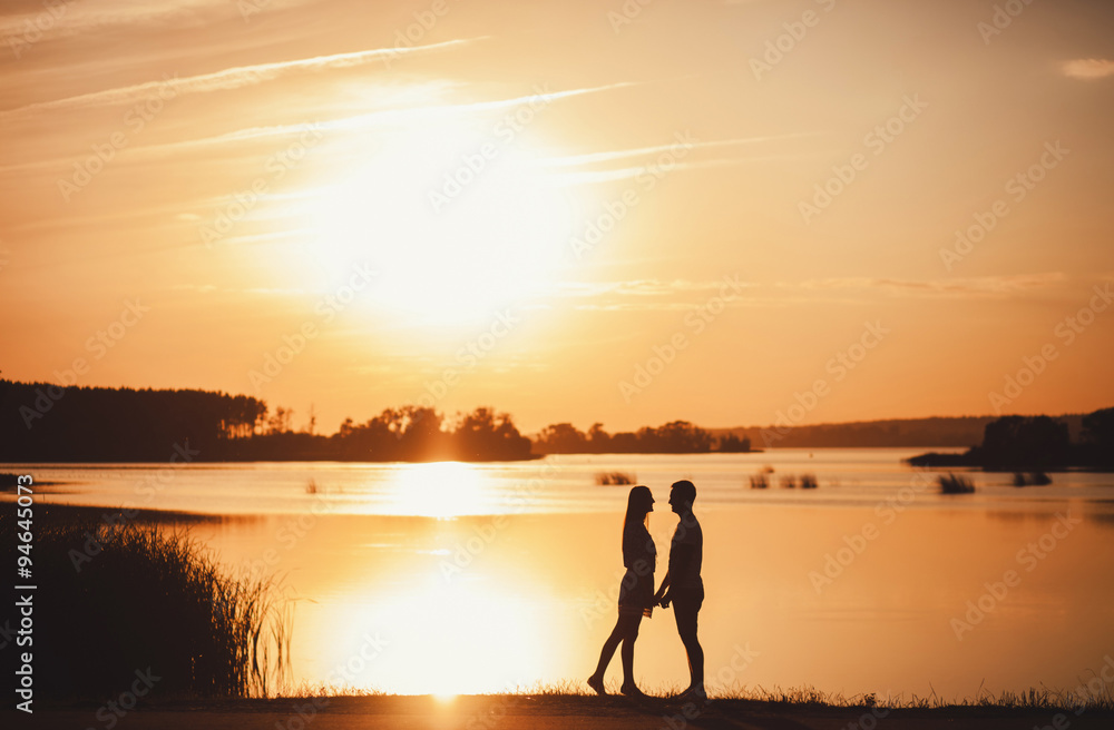 Fototapeta premium Romantic couple standing at sunset. copy space