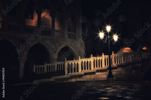 bridge via the Palace channel, a lamp and a wall of Doges Palace at night during a rain, Venice