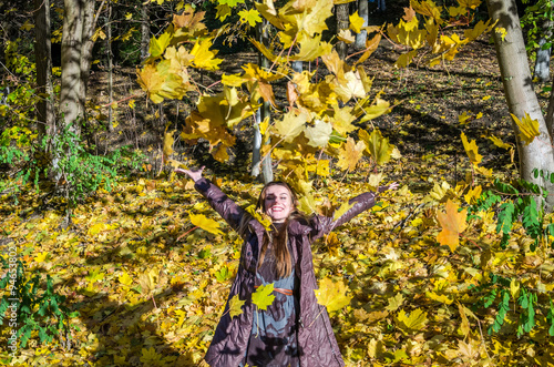 The beautiful young girl a happy woman smiling and holding a yellow maple leaves walking in autumn park