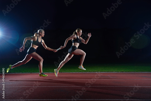 athletic runners passing baton in relay race photo