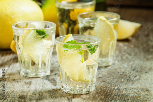 Carbonated lemonade with lemon slices and mint on an old wooden