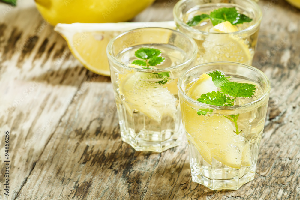 Fototapeta premium Carbonated lemonade with lemon slices and mint on an old wooden