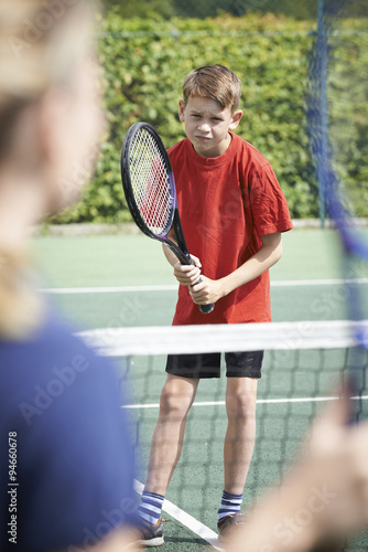 Female Tennis Coach Giving Lesson To Boy