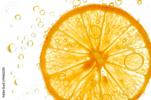 Fresh orange slice in water with bubbles on white background