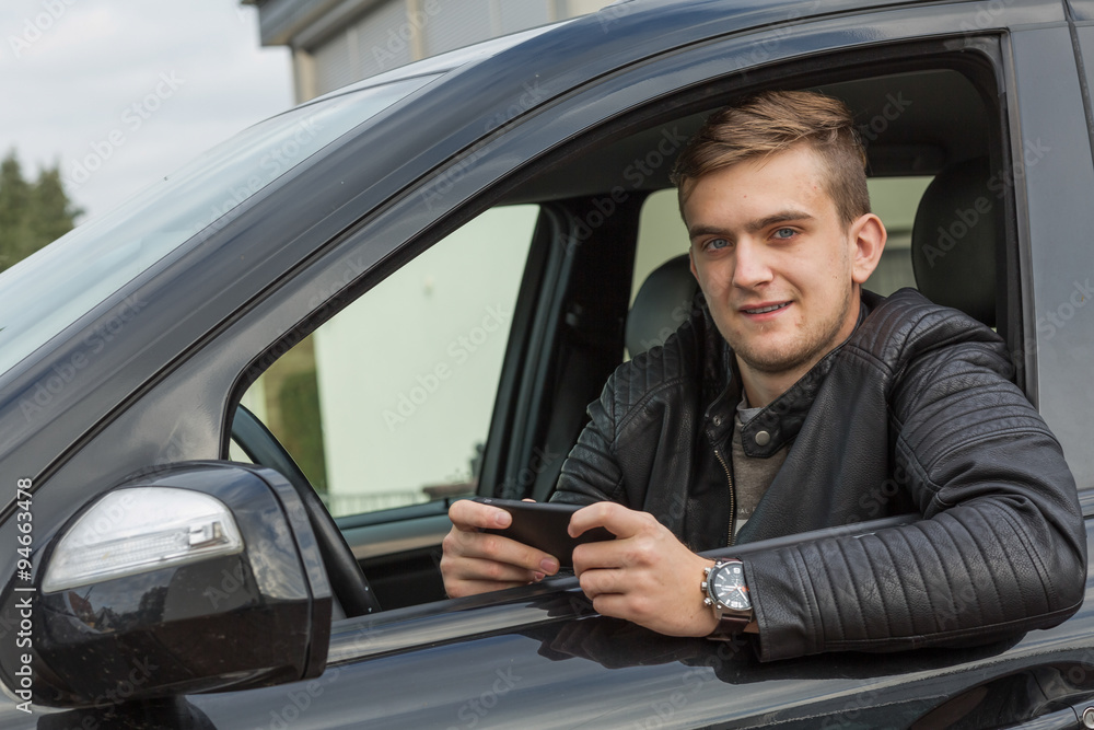 blonde young adult using smartphone and sitting inside of a car blonde young adult using smartphone and sitting inside of a car