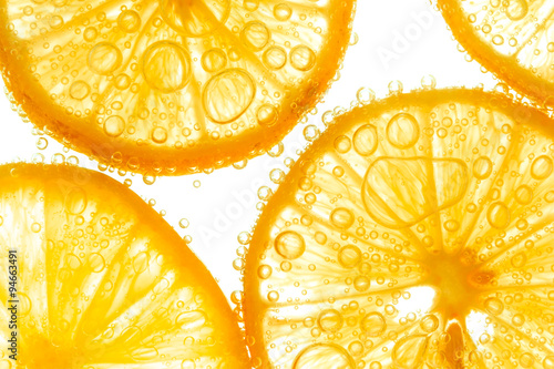 Fresh orange slice in water with bubbles on white background
