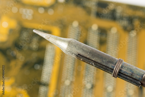 Detail of plated tip of a soldering iron over a printed circuit board