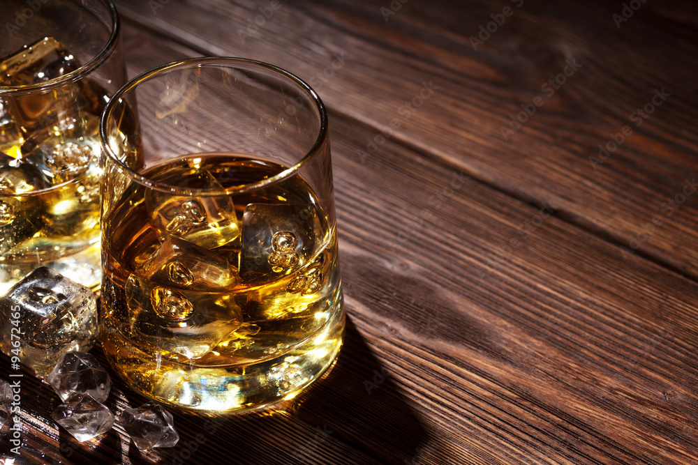Glasses of whiskey with ice on wood Glasses of whiskey with ice on wood