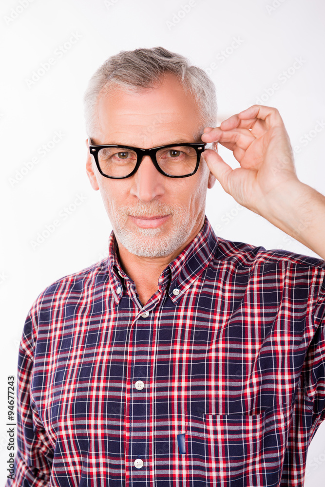 Confident gray aged man holding glasses with one hand Confident gray aged man holding glasses with one hand