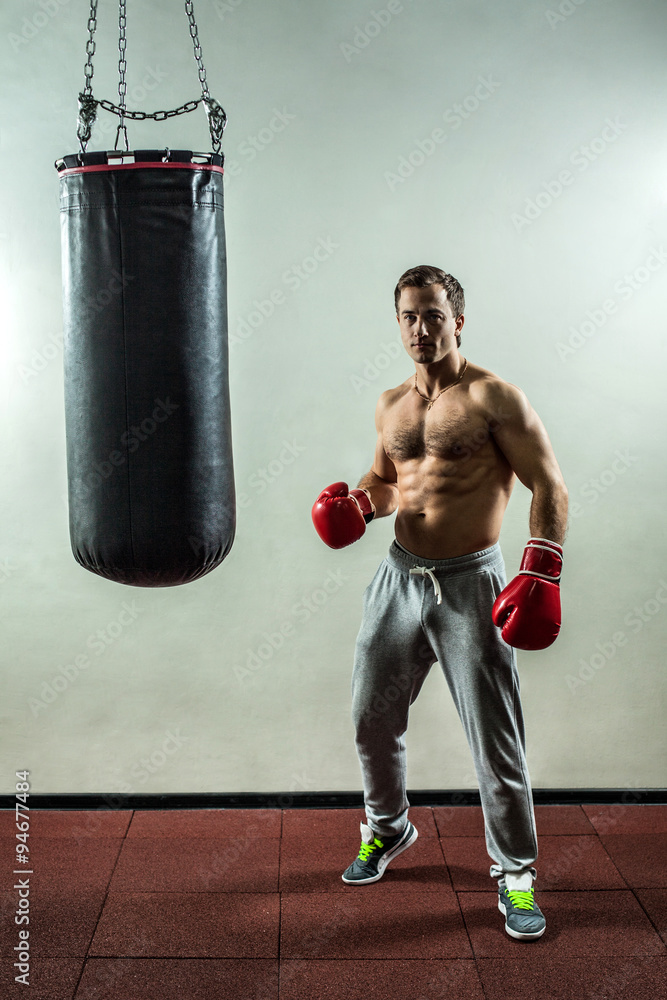 Muscular boxer near the boxing bag.