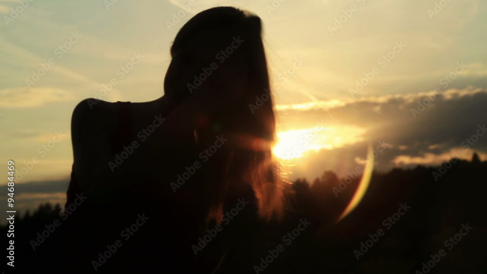 A silhouette of a woman on a sunset comb her hair A silhouette of a woman on a sunset comb her hair