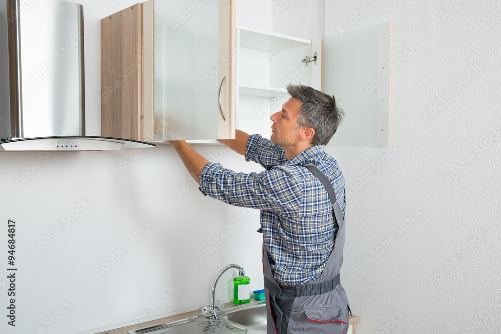 Serviceman Fixing Cabinet With Screwdriver In Kitchen Serviceman Fixing Cabinet With Screwdriver In Kitchen