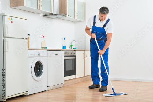 Worker Mopping Floor In Kitchen At Home