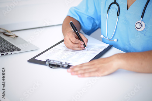 Portrait of unknown male surgeon doctor holding his stethoscope and filling up medical prescription