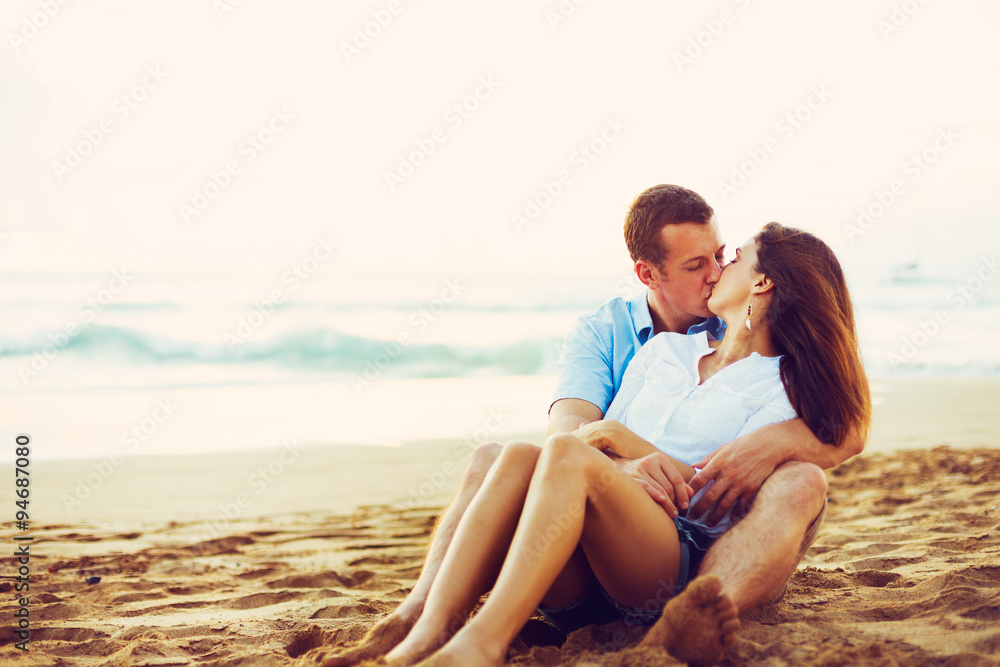 Couple Relaxing on the Beach Kissing and Watching the Sunset
