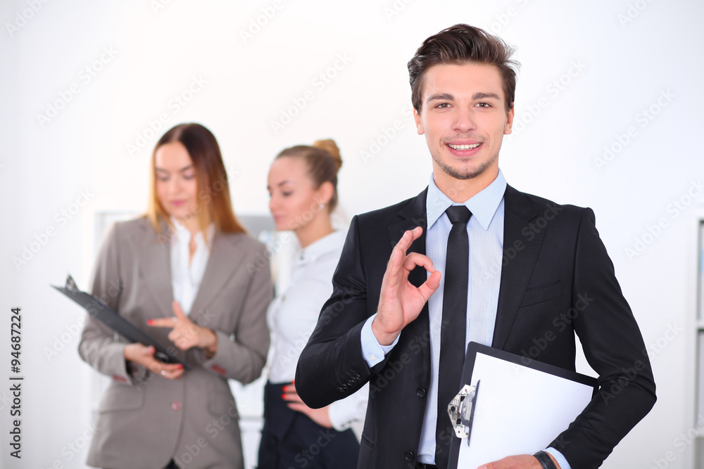 Cheerful business man in office with colleagues in the background, sturt up team Cheerful business man in office with colleagues in the background, sturt up team